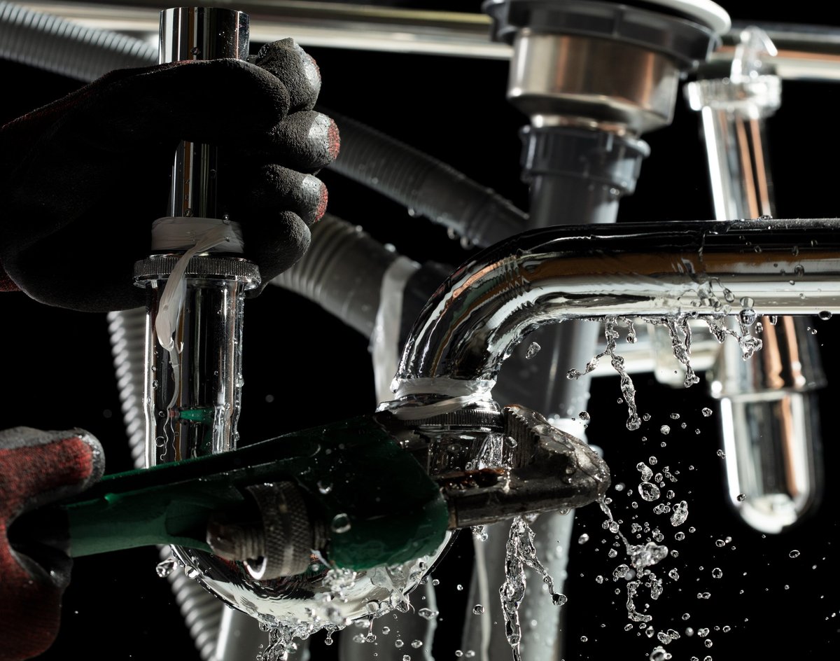 Plumber used wrench to tighten loose nut on water drain pipe under kitchen sink